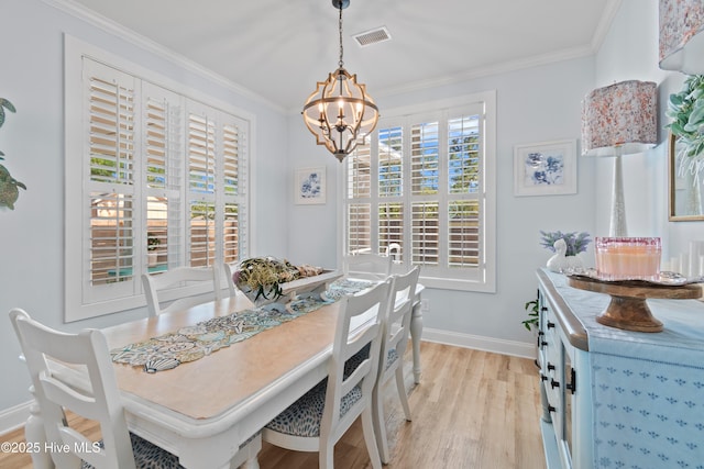 dining space featuring an inviting chandelier, light wood finished floors, baseboards, visible vents, and ornamental molding