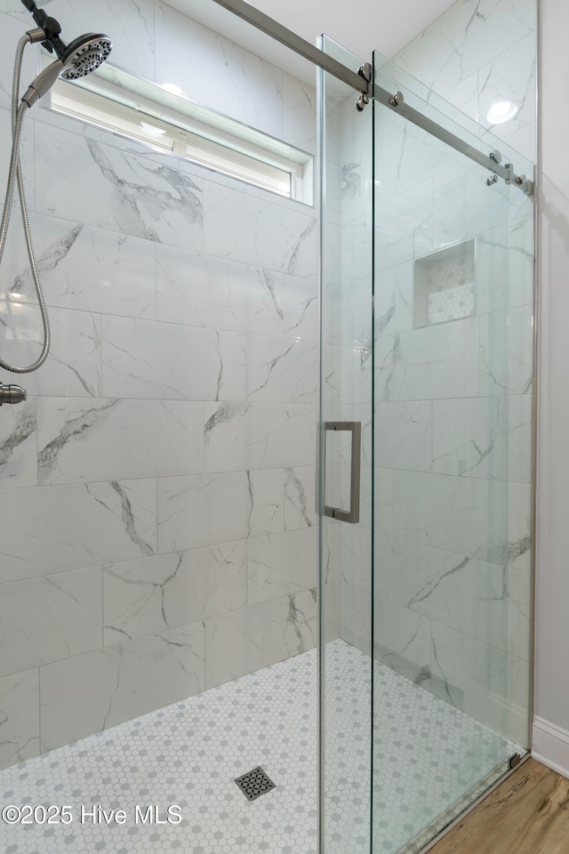 bathroom featuring a marble finish shower and wood finished floors