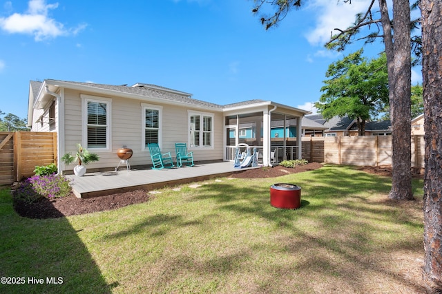 rear view of house with a sunroom, a fenced backyard, a yard, and a deck