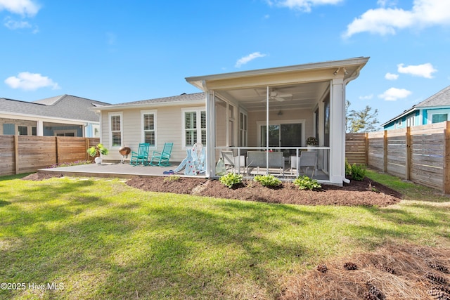 rear view of house featuring a sunroom, a fenced backyard, a yard, and a patio