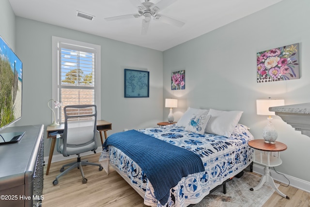 bedroom featuring baseboards, ceiling fan, wood finished floors, and visible vents