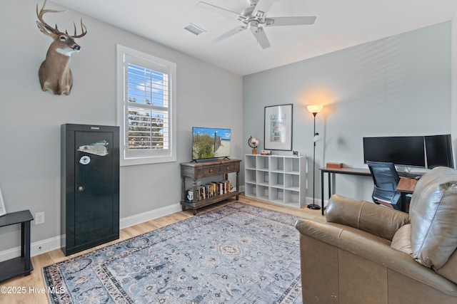 living room featuring a ceiling fan, baseboards, visible vents, and wood finished floors