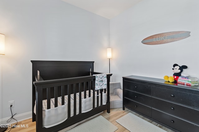 bedroom featuring a nursery area and wood finished floors