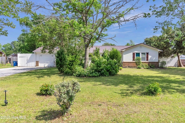 view of front of house featuring brick siding, a front lawn, fence, and driveway