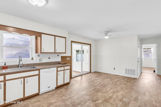 kitchen with a sink, dishwasher, a ceiling fan, white cabinetry, and visible vents