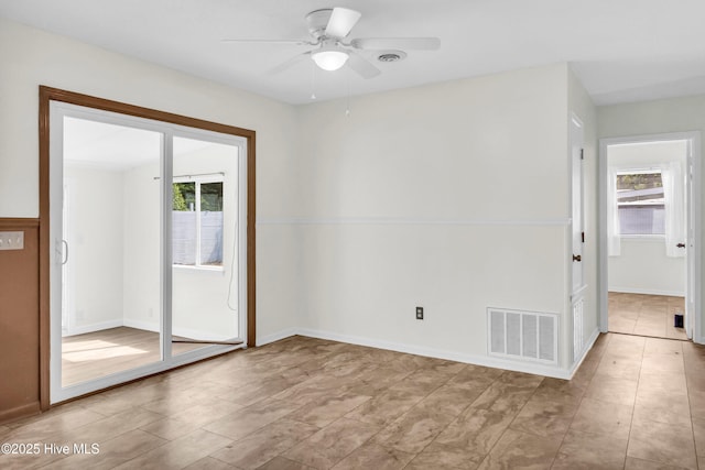empty room featuring visible vents, ceiling fan, and a wealth of natural light
