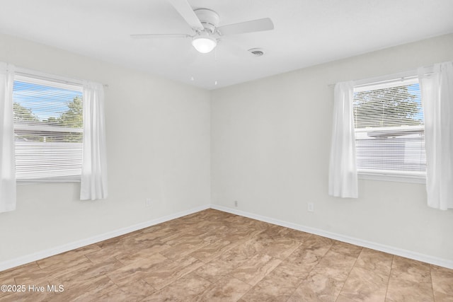 empty room with a ceiling fan, baseboards, and a healthy amount of sunlight
