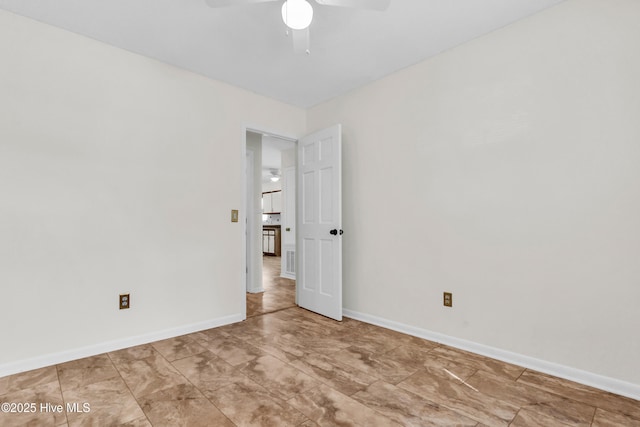 unfurnished room with ceiling fan and baseboards