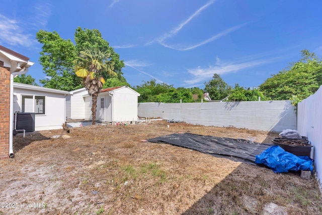view of yard with a storage shed, an outbuilding, and a fenced backyard