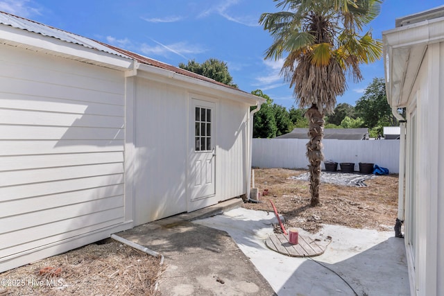 property entrance featuring a patio area, fence, and metal roof