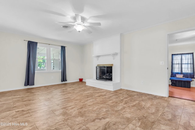 unfurnished living room with crown molding, a large fireplace, ceiling fan, and baseboards