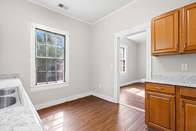 kitchen featuring visible vents, ornamental molding, wood finished floors, light countertops, and a sink