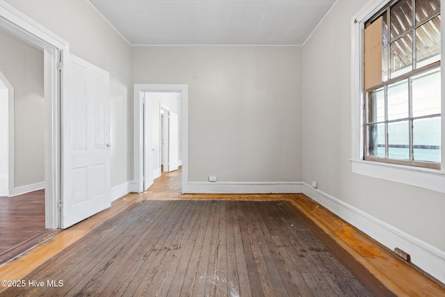 spare room featuring baseboards and wood-type flooring