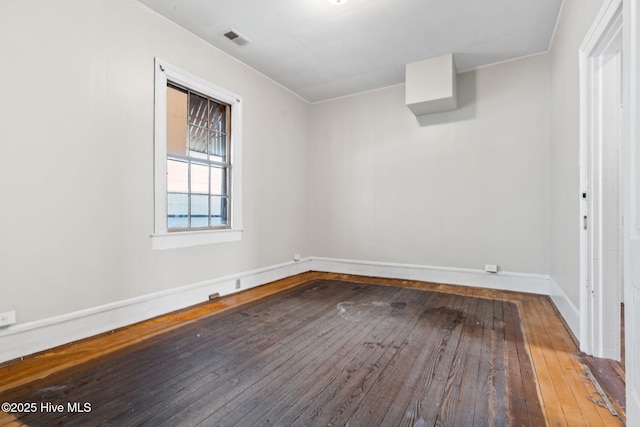 empty room with wood-type flooring, baseboards, and visible vents
