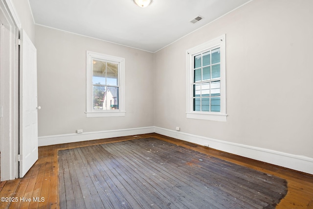 unfurnished room with baseboards, visible vents, and hardwood / wood-style flooring