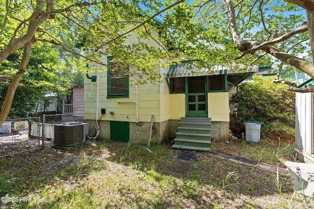 back of house featuring central AC unit, fence, and entry steps