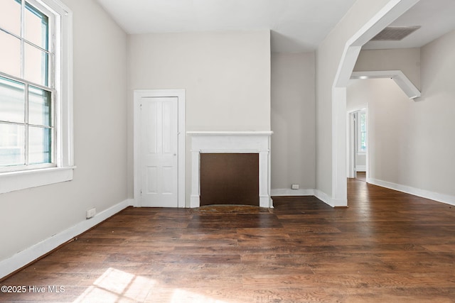 unfurnished living room featuring baseboards, plenty of natural light, wood finished floors, and visible vents