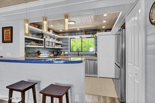 109 Teakwood Dr Unit 802, Carolina Beach, NC 28428 - kitchen with stainless steel appliances, light wood-type flooring, a breakfast bar area, wooden ceiling, and open shelves