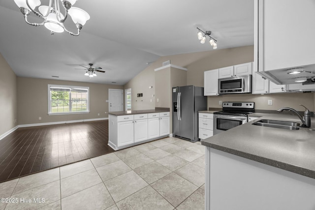 308 E Ashe St, Burgaw, NC 28425 - kitchen with a sink, vaulted ceiling, dark countertops, stainless steel appliances, and white cabinets