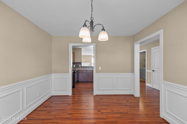 2202 Sweet Bay Dr Unit B, Greenville, NC 27834 - unfurnished dining area featuring a chandelier, a wainscoted wall, dark wood-type flooring, and a decorative wall