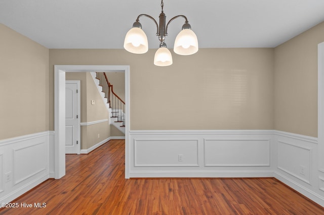 2202 Sweet Bay Dr Unit B, Greenville, NC 27834 - empty room featuring a chandelier, a wainscoted wall, wood finished floors, stairs, and a decorative wall