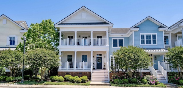 view of front of house with covered porch, a standing seam roof, a balcony, and stairs