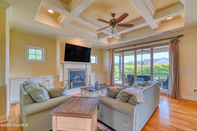 living area with crown molding, ceiling fan, coffered ceiling, and light wood-style flooring
