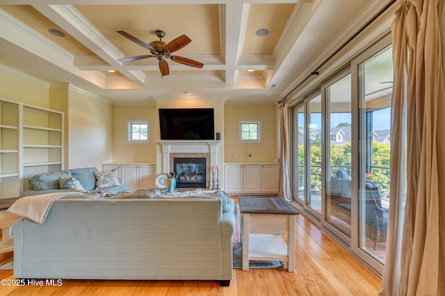 living room featuring crown molding, a ceiling fan, a glass covered fireplace, and a healthy amount of sunlight