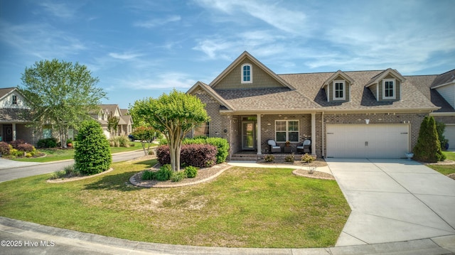 craftsman house with a front yard, brick siding, concrete driveway, an attached garage, and a porch