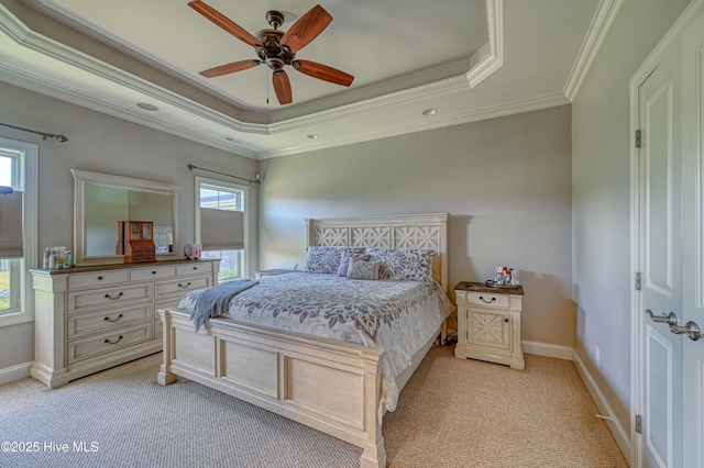 bedroom with a tray ceiling, light colored carpet, ornamental molding, and baseboards