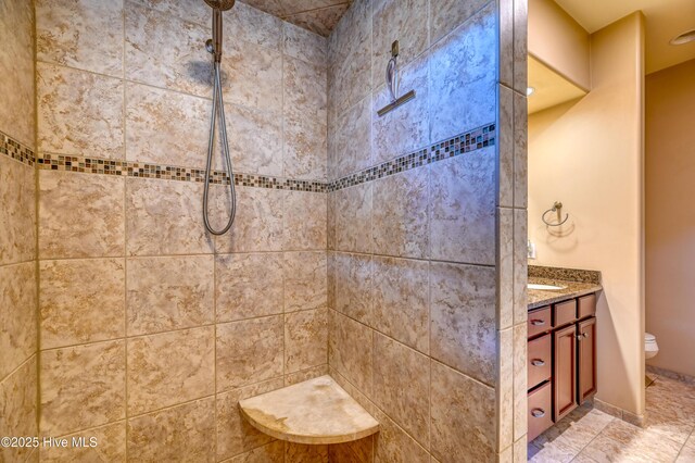 bathroom featuring toilet, a tile shower, and vanity