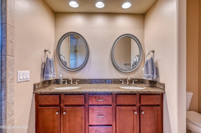 bathroom with double vanity, a sink, and toilet