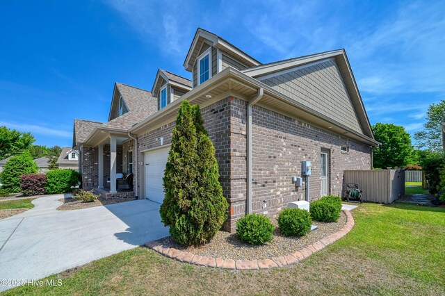 view of side of home featuring a lawn, fence, brick siding, concrete driveway, and an attached garage