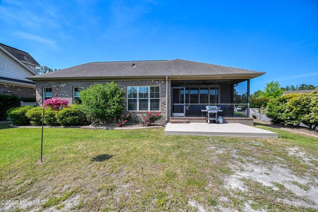 back of house featuring brick siding, a yard, a sunroom, and a patio