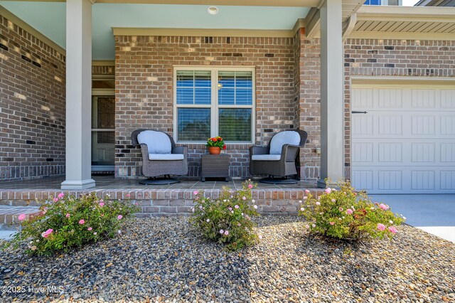 doorway to property featuring an attached garage, driveway, and brick siding