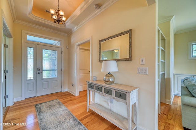 entryway with visible vents, crown molding, baseboards, a chandelier, and light wood-style flooring