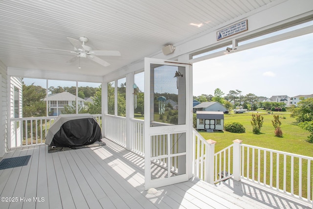 deck featuring a ceiling fan, a yard, a sunroom, and grilling area