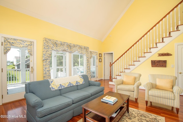 living area featuring crown molding, wood finished floors, a healthy amount of sunlight, and stairway