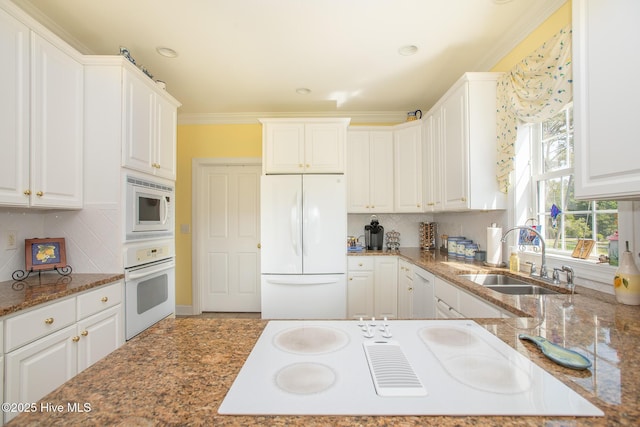 kitchen featuring white appliances, white cabinets, a sink, and tasteful backsplash