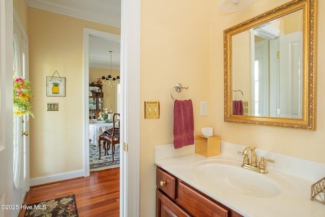 bathroom with crown molding, wood finished floors, vanity, baseboards, and a wealth of natural light