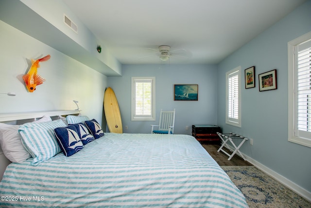 bedroom with baseboards, visible vents, multiple windows, and wood finished floors