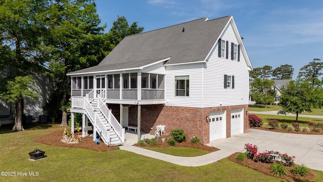 rear view of house featuring driveway, roof with shingles, a sunroom, a garage, and a yard