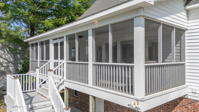 view of property exterior with a sunroom, roof with shingles, and brick siding