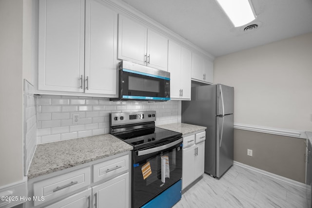 kitchen featuring appliances with stainless steel finishes, white cabinets, light stone countertops, and tasteful backsplash