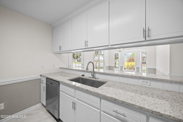 kitchen with stainless steel dishwasher, light stone countertops, white cabinetry, a sink, and a wealth of natural light