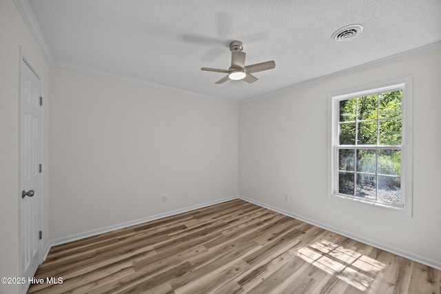 empty room with ceiling fan, visible vents, ornamental molding, and wood finished floors