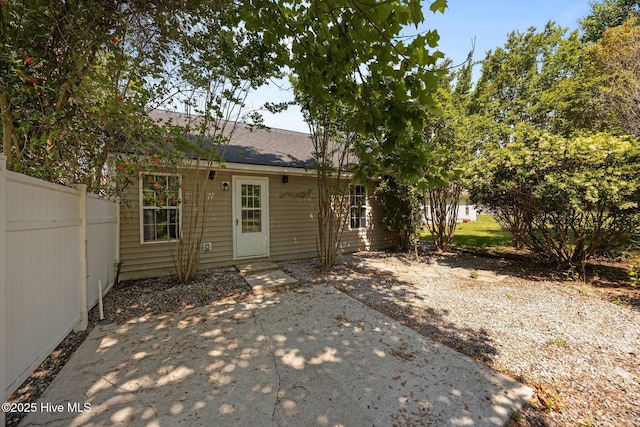 rear view of house featuring fence, a patio, and a shingled roof