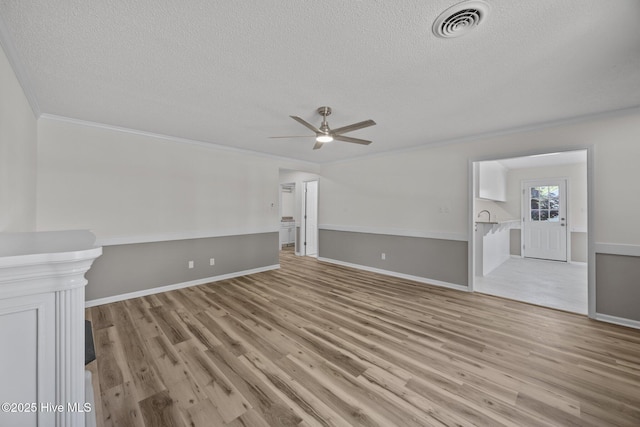 unfurnished living room with light wood-style flooring, a textured ceiling, and visible vents