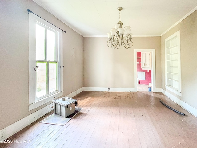 unfurnished dining area featuring crown molding, baseboards, wood-type flooring, and a chandelier