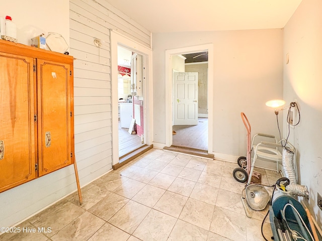 interior space with light tile patterned floors and wood walls
